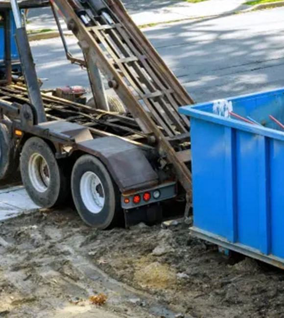 dumpster being loaded onto truck trailer